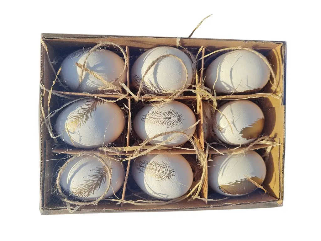 Verpakking van 9 witte decoratieve eieren met gouden veerprint en raffia stro-.webp